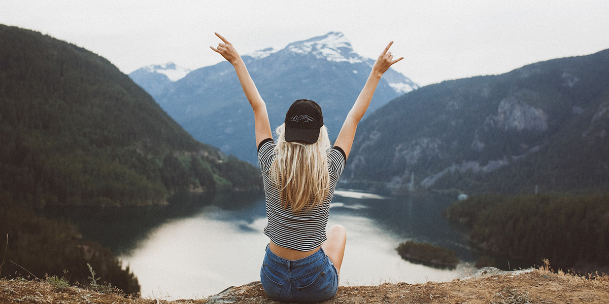 崖の上で両手を上げる女性